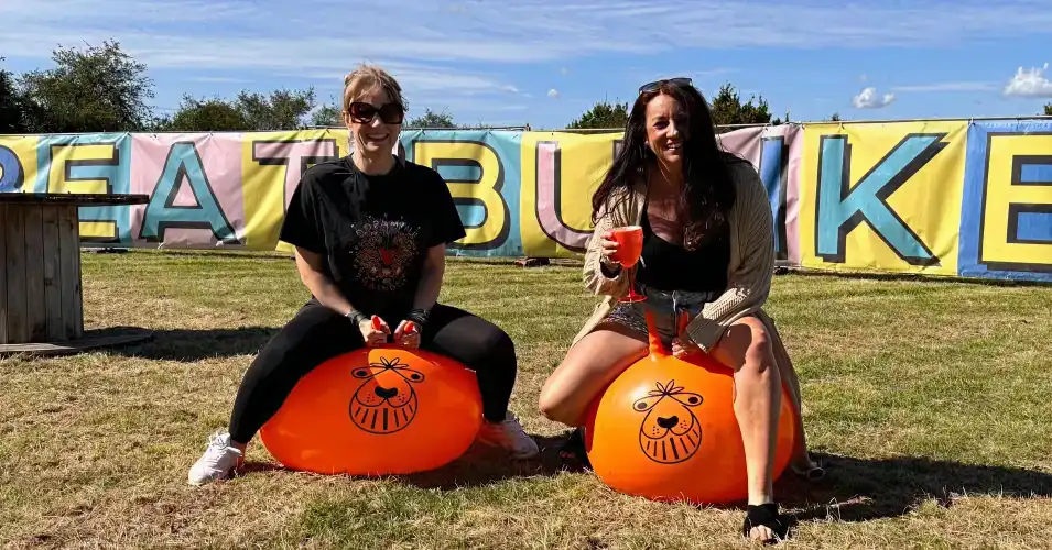 Festival-goers racing on space hoppers in the summer sun.