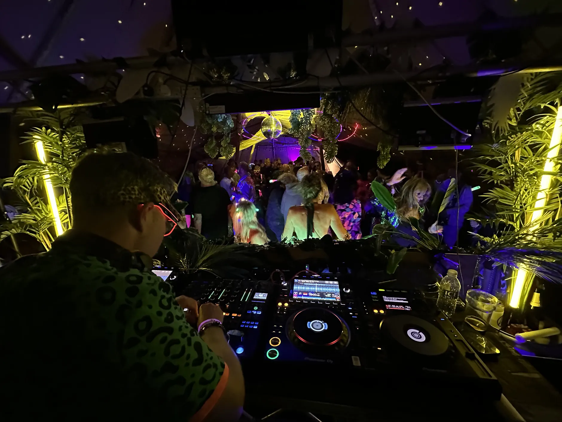 A DJ playing to a crowd under neon jungle lighting at Beat Bunker
